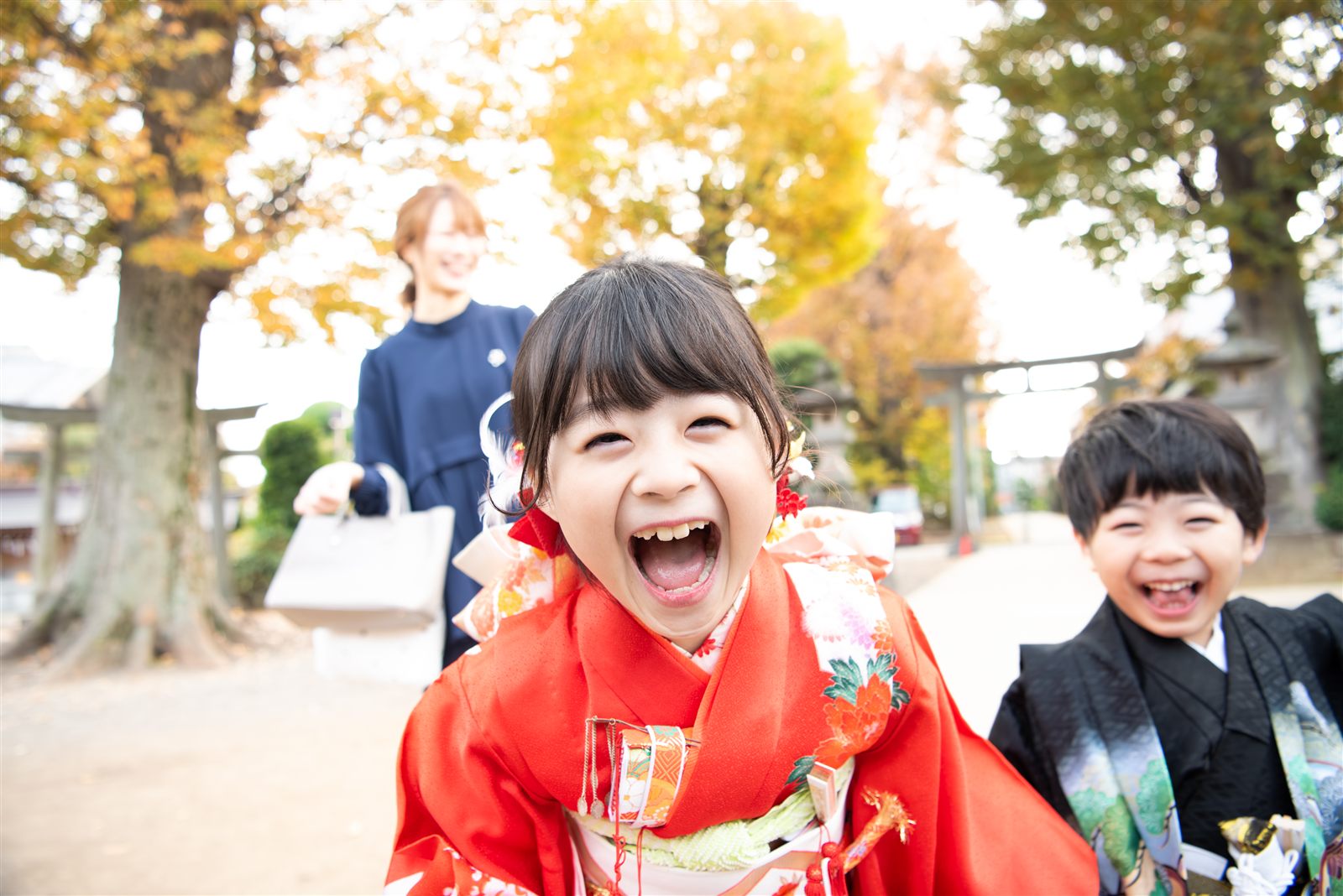 赤い着物で満面の笑みを見せる七五三の女の子と羽織袴の男の子