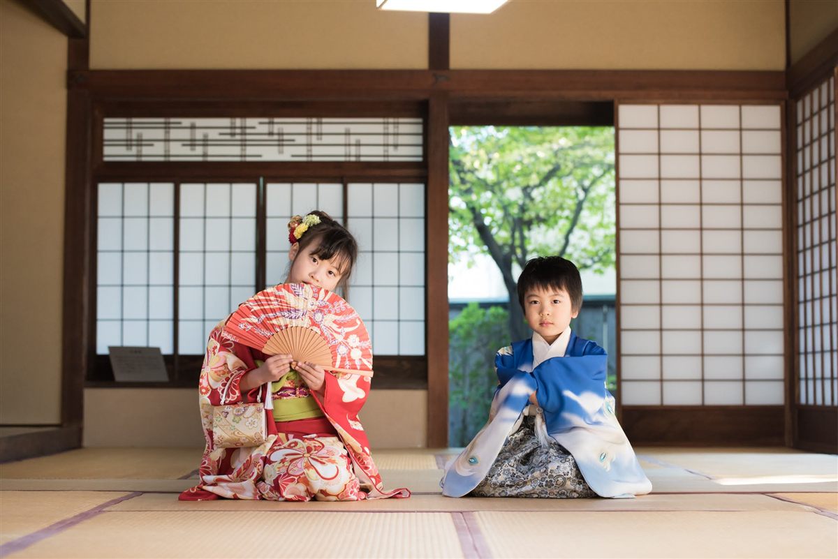 和室で扇子を手に正座する七五三の姉と弟