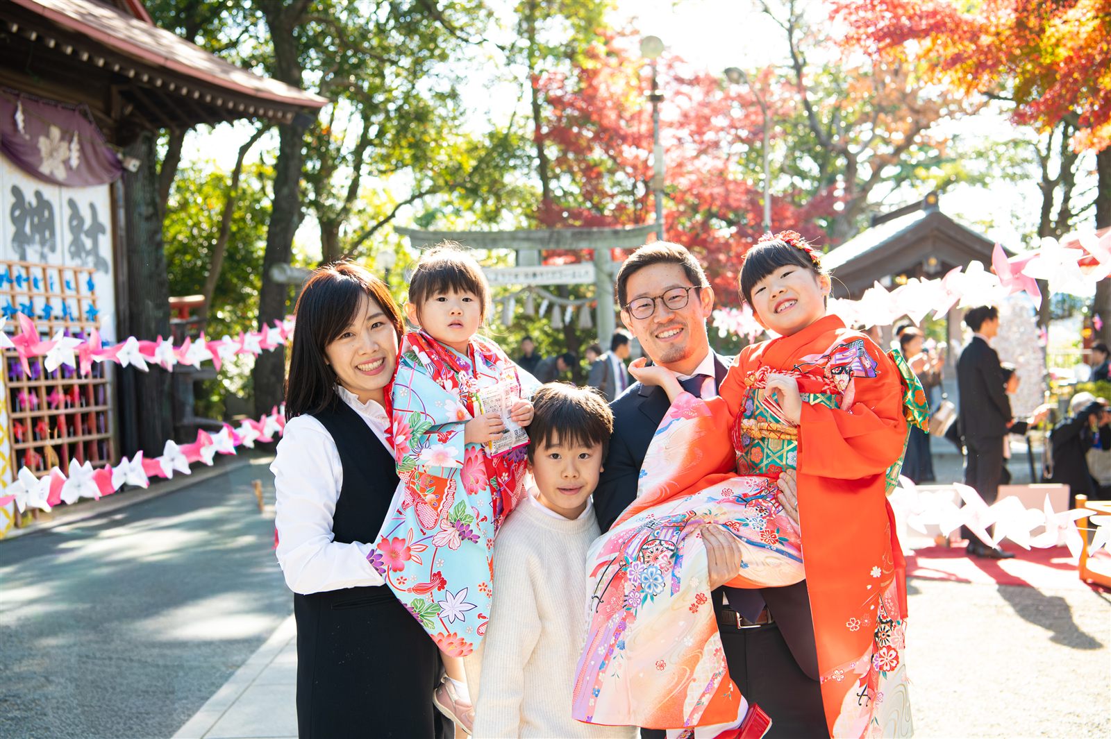 神社の参道に並んで笑う七五三のご家族4人