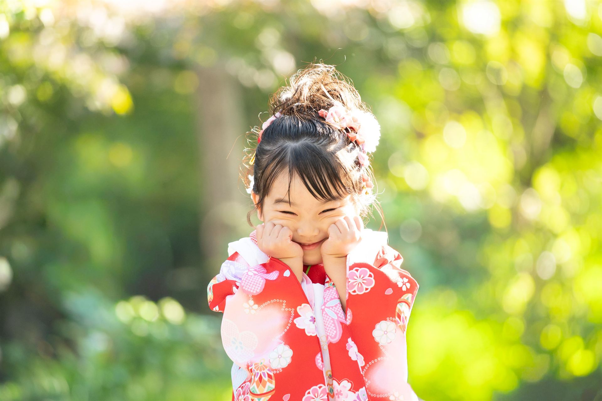 赤い着物で頬に手をあててはにかむ七五三の女の子