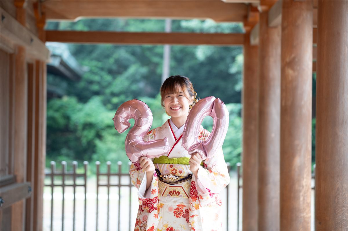 神社の回廊でバルーンを手にほほ笑む振袖姿の女性